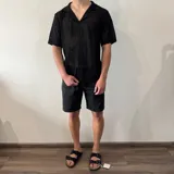 Camisa negra tejida con diseño calado, corte regular, cuello tipo polo y cierre frontal con botones.