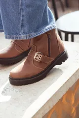 Bota corta color marrón de cuero, con hebilla metálica y cierre lateral.