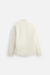 Camisa color crudo de algodón con acabado cepillado, corte relaxed fit, cuello solapa, manga larga con puño abotonado, bolsillo de parche en el pecho, efecto lavado y cierre frontal abotonado.