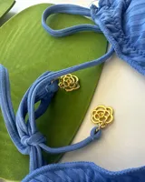 Bikini de dos piezas color azul, con corpiño triangular con volados y tirantes finos ajustables. La bombacha es de corte regulable con lazos laterales y tiene un pequeño frunce en la parte trasera.