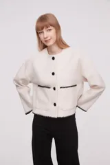 Chaqueta color marfil con diseño holgado, manga larga y botones frontales.