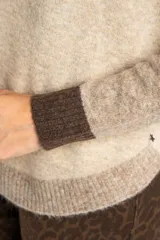 Sweater de punto con diseño color block en tonos beige, marrón y bordeaux.