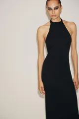 Vestido largo negro, corte recto, con cuello halter que se ata en la nuca y espalda descubierta.