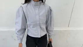 Campera entallada de bengalina color celeste, con cierre frontal, cuello subido, bolsillos delanteros y mangas acampanadas con botones a presión en los puños.