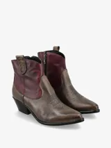 Botín de cuero negro y marrón, de estilo texano, con punta fina, costuras decorativas y taco bajo.