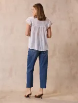 Blusa color marrón claro de algodón con bordados y calados blancos. Tiene cuello a la base, escote en V con lazo de ajuste y mangas cortas amplias.