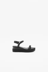 Sandalia negra con plataforma forrada en yute trenzado y doble tira de cuero con tachas niqueladas.