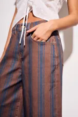 Pantalón de jean tiro medio, corte wide leg, confeccionado en tela de algodón con rayas verticales marrones y azules.