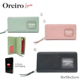Billetera larga color verde agua con cierre perimetral y correa de mano. Diseño con textura de labios y logo de la marca en el frente.