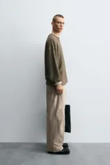 Pantalón de jean color beige, corte holgado y amplio en toda la pierna, tiro medio, tejido rígido, cinco bolsillos, efecto lavado y detalle de pinzas en perneras.