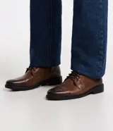 Bota de cuero marrón con caña corta, cierre de cordón y suela negra.