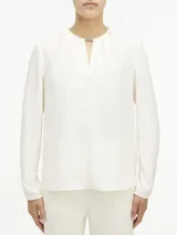 Blusa de manga larga de poliéster reciclado, con barra metálica en el cuello y diseño clásico.