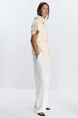 Camiseta color crudo de algodón con cuello redondo, manga corta caída y cintura ajustable con cordón.