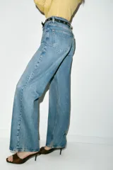 Jeans de tiro alto color azul claro, con cinco bolsillos y pernera recta que se estrecha hacia el tobillo. Incluye un cinturón negro con detalles metálicos.