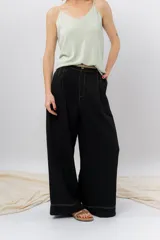 Pantalón negro de corte ancho y fluido, tiro medio con presillas para cinturón, bolsillos laterales funcionales y pinzas delanteras.