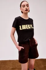 Remera gris acero de algodón pima, de corte holgado y largo a la cadera, con estampado frontal amarillo con la palabra 'Liberté'.