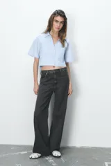 Camisa celeste de popelín con cuello solapa, escote pico y manga corta. Presenta dos bolsillos delanteros de parche y cierre frontal con botones.