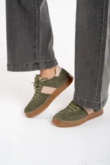 Zapatilla deportiva de cuero color verde oliva con detalles en rosa y suela marrón.