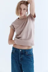 Remera color beige de corte recto en punto suave de algodón con cuello redondo ribeteado y hombros ligeramente caídos.