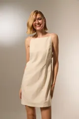 Vestido corto color beige, de algodón, con escote cuadrado y tirantes finos ajustables. Presenta aberturas laterales con detalle de estampado animal print.