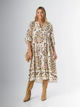 Vestido midi de algodón italiano, color blanco con estampado boho chic en tonos naranja, marrón y verde. Tiene corte oversized, mangas 3/4 con volados y cinturón de soga trenzada con hebilla circular.