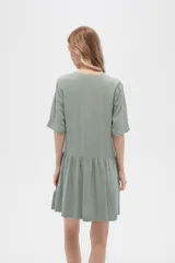 Vestido corto color crema, de corte holgado, con cuello en V y botones frontales.