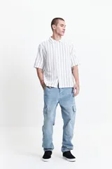 Camisa de manga corta con corte oversize, a rayas verticales blancas y grises, con cuello clásico y cierre frontal con botones. Confeccionada en algodón.