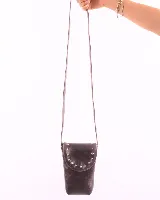 Porta celular negro de cuero charol, con correa fina y solapa con tachas plateadas.