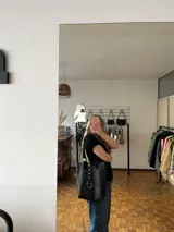 Bolso tote negro de cuero con asas cortas y largas. Presenta un bolsillo interno y cierre con dos botones.