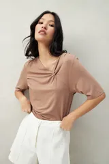 Remera de modal color marrón claro, de manga corta, con cuello asimétrico y detalle de nudo con frunces.