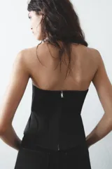 Top bustier negro de satén con escote corazón y hombros descubiertos. Cierre trasero con cremallera metálica.