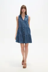 Vestido gris de algodón, largo hasta la rodilla, con cuello camisero, sin mangas, cierre frontal de botones blancos y falda con volados.