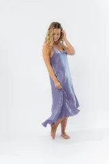 Vestido midi color lila metálico de breteles finos regulables, escote en V y ruedo asimétrico con leve vuelo.