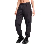Pantalón deportivo negro de tejido woven con cintura elástica, corte holgado y logo de Nike bordado en blanco en la pierna izquierda.