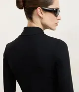 Campera deportiva negra de manga larga y cuello alto, con cierre frontal. Presenta recortes en el torso y bolsillos laterales con cierre.