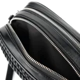 Bandolera negra de símil cuero con diseño texturizado. Tiene formato rectangular, acceso con cierre, correa regulable y herrajes plateados. Cuenta con dos compartimentos, un bolsillo interno con cierre, un bolsillo interno abierto y un bolsillo externo con botón imantado. El interior está forrado en tela de algodón y poliéster.