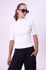 Blusa blanca de tejido de punto acanalado, con cuello alto y mangas cortas.