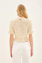Sweater color crema tejido con punto desagujado en hilado de algodón y poliéster. Tiene ajustes en mangas y cintura, y pequeños volados en las terminaciones.
