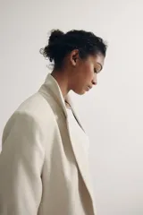 Blazer color crema con solapas de muesca, mangas tres cuartos fruncidas y bolsillos delanteros con solapa. Sin cierre. Forrado.