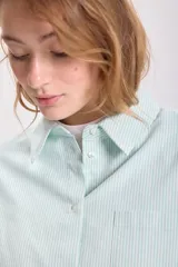 Camisa de manga larga con cuello clásico, corte recto y cierre frontal con botones. Diseño a rayas verticales finas en color verde agua y blanco.