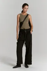 Pantalón de gabardina negro con cintura elástica y tiras regulables, con múltiples bolsillos y cinturón con cierre metálico.