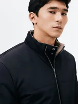 Campera acolchada reversible, color negro con interior beige, cuello mao y cierre frontal con cremallera.