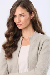 Campera tejida de abrigo color beige, con cierre frontal, cuello alto y bolsillos laterales.