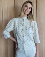 Camisa color beige claro con cuello con volados y mangas 3/4 abullonadas.