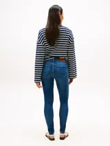 Jean de mujer de tejido denim rígido, color azul medio con efecto desteñido en muslos y rodillas. Presenta un corte de pierna ancha y talle alto, con cierre de cremallera y botón, y estilo de cinco bolsillos.