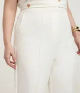 Pantalón de vestir blanco, modelo flare con corte sastrero, bolsillos laterales y elástico en la espalda.