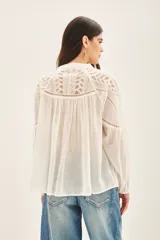 Camisa blanca de algodón con corte amplio, bordado a tono en canesú delantero, trasero y hombros. Mangas largas con volumen y elástico en los puños.