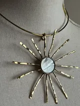 Gargantilla dorada con dije en forma de sol con centro de nácar.