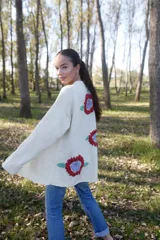 Maxi cardigan color crema de lana merino con bordado de flores rojas y azules.