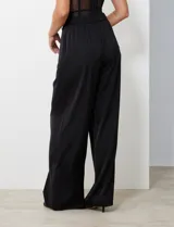 Pantalón palazzo de tiro alto color violeta, de satén. Tiene pretina delantera con pasadores, botón y cierre, pretina trasera elastizada y bolsillos verticales delanteros.